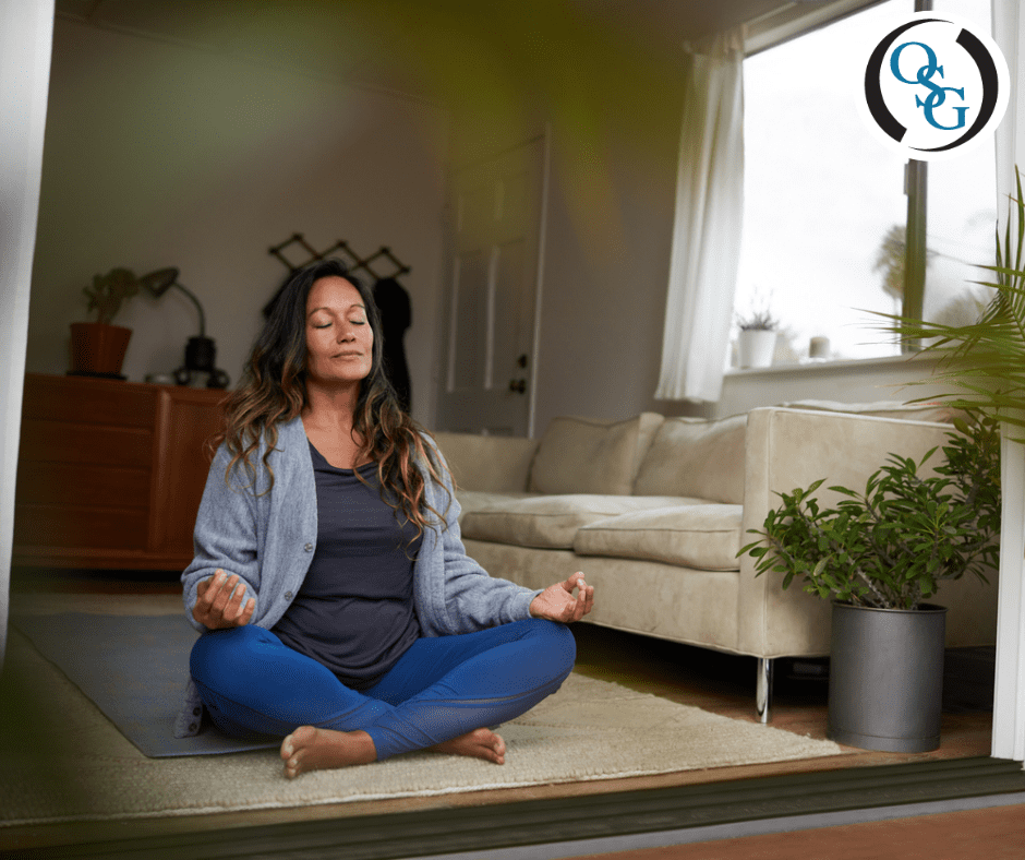 A woman calmly meditating on the floor of her living room
