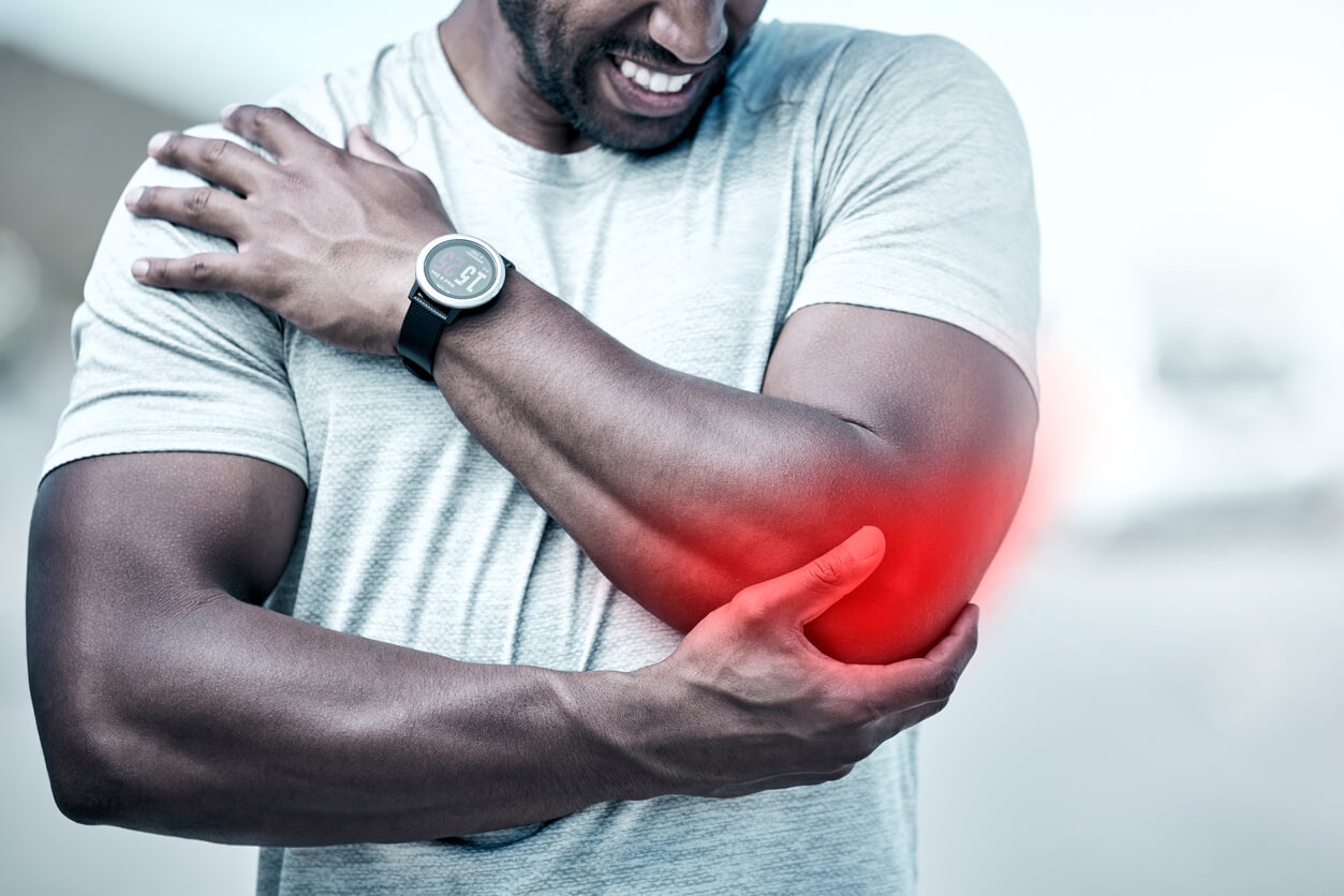 Closeup fit man holding his elbow in pain while exercising outdoors. Unrecognizable male athlete suffering with a joint injury highlighted by glowing cgi. You can get hurt during a workout