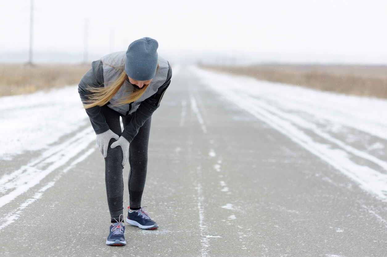Injuries - sports running knee injury on woman. Winter marathon