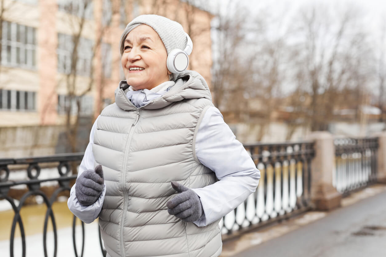 Waist up portrait of active senior woman running outdoors in winter and smiling happily, copy space