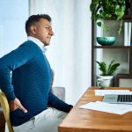 Shot of a businessman suffering from back pain while working at home