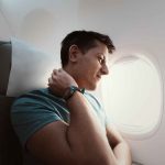 A man suffers from severe neck pain during a long flight in an uncomfortable position on an airplane. Joint pain travel tips