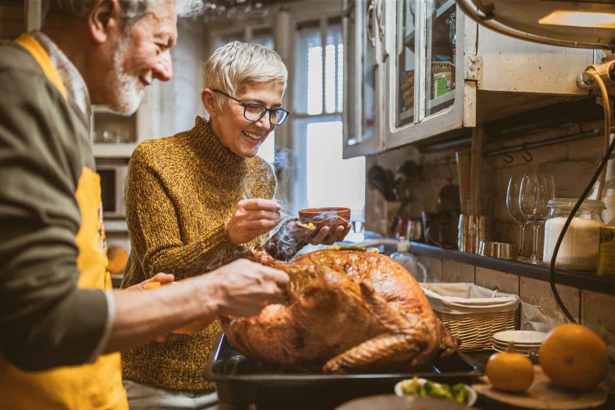 Happy senior couple decorating turkey on Thanksgiving day.