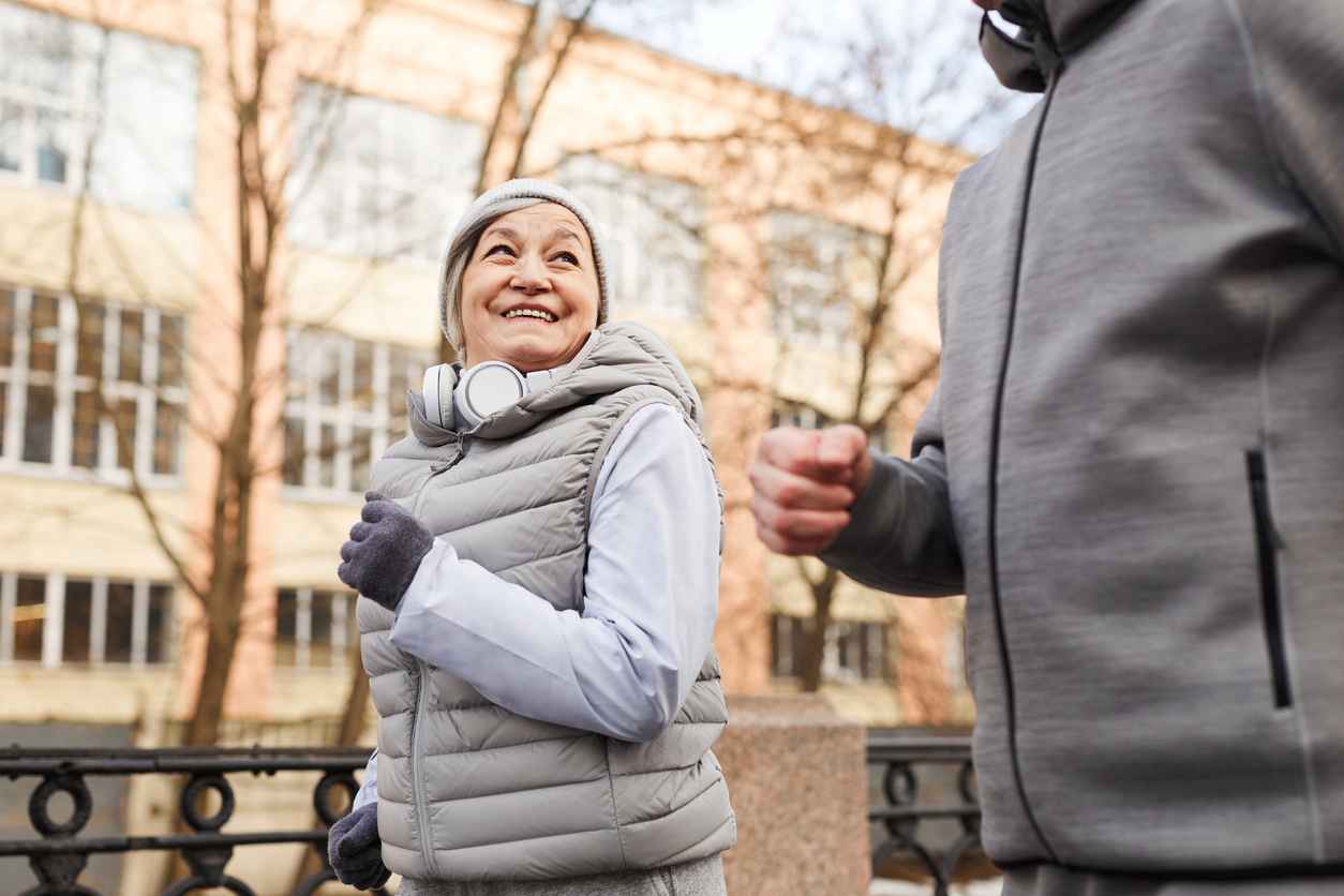 Low angle portrait of active senior couple running outdoors in winter and smiling happily