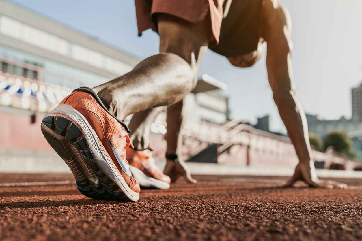 Close up of male athlete getting ready to start running on track . Focus on sneakers; The Importance of Regular Orthopaedic Check-ups for Recreational Athletes
