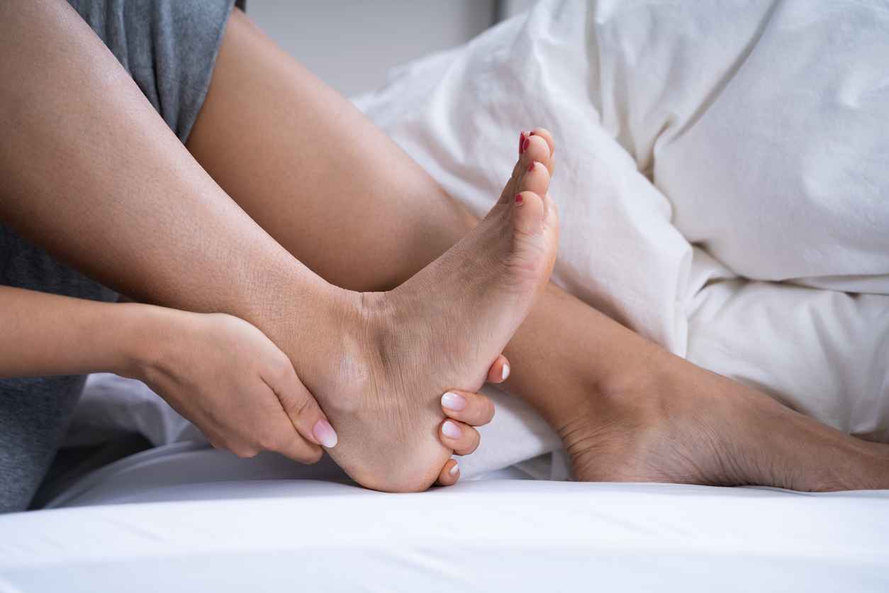 Woman Feeling Achilles Heel Pain In Bed; What is Achilles Tendonitis?