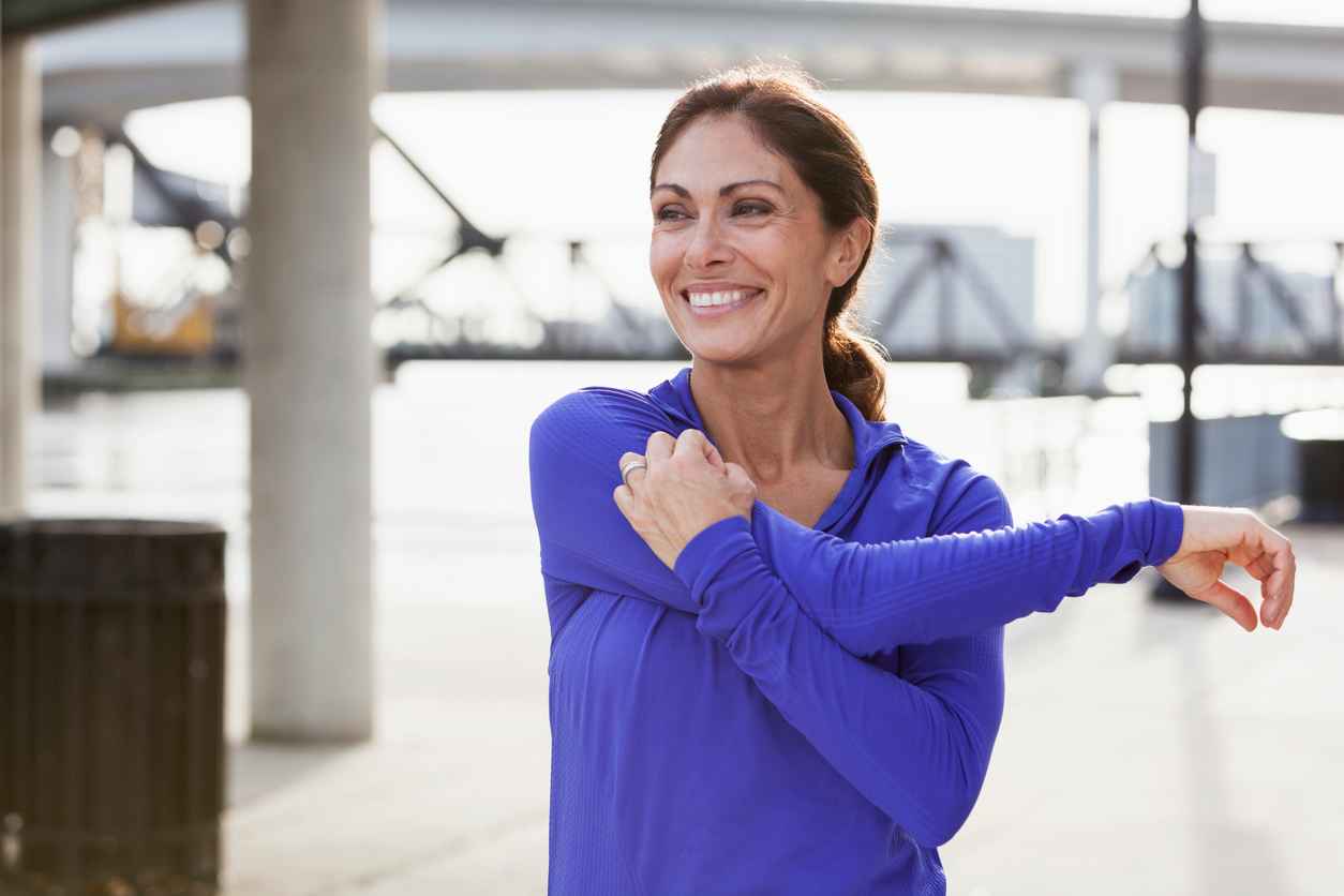 Mature woman taking a break from running to stretch her arms, looking at the view on the waterfront; Orthopaedic Tips for Maintaining Joint Health
