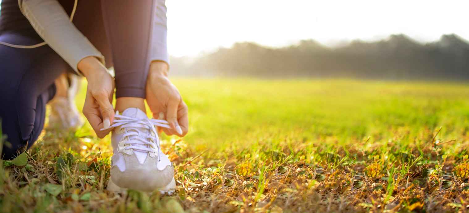 young woman runner tying her shoes preparing for a jog outside at morning; The Runner's Guide to Spring