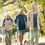 Hiking, elderly and people, happy outdoor with nature, fitness and fun in park, exercise group trekking in Boston. Diversity, friends and happiness with hike, active lifestyle motivation and senior.