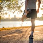 Man runner stretching leg and feet and preparing for jogging and running in public park outdoors at sunset, Active and healthy lifestyle concept.