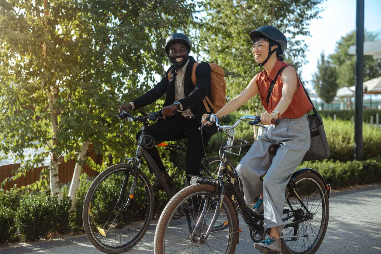 Two people enjoying a leisurely bike ride through a park setting. The sun shines brightly, casting a warm glow over the scene, and highlighting the joy of outdoor activities.