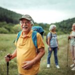 Portrait of cheerful senior man hiking in forest with his family