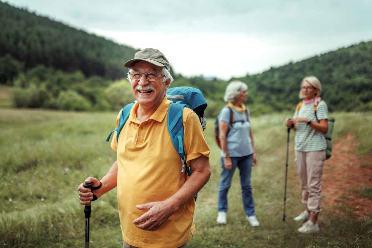 Portrait of cheerful senior man hiking in forest with his family