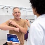 Mature Latin American patient talking to an orthopedist about pain in his shoulder