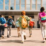 Little kids schoolchildren students running hurrying to the school building for classes lessons from to the school bus. Welcome back to school. The new academic semester year start