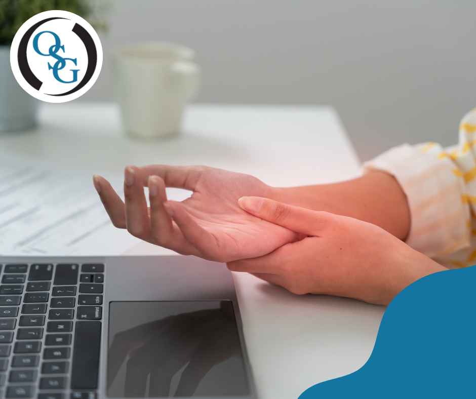 Person with carpal tunnel syndrome grabbing their wrist in pain in front of their laptop.