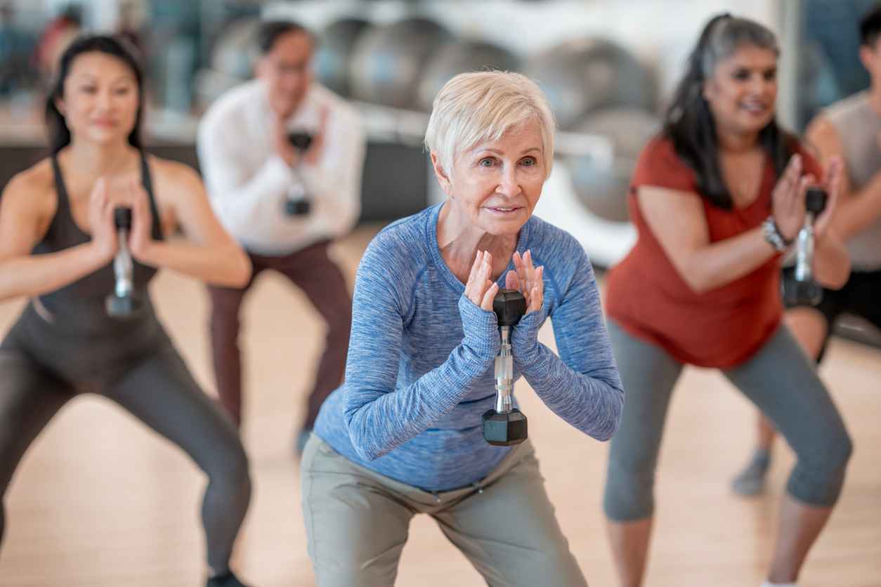 A diverse group of individuals participates in a strength training session at a fitness studio, performing exercises with focus and determination while fostering a sense of community and wellness.